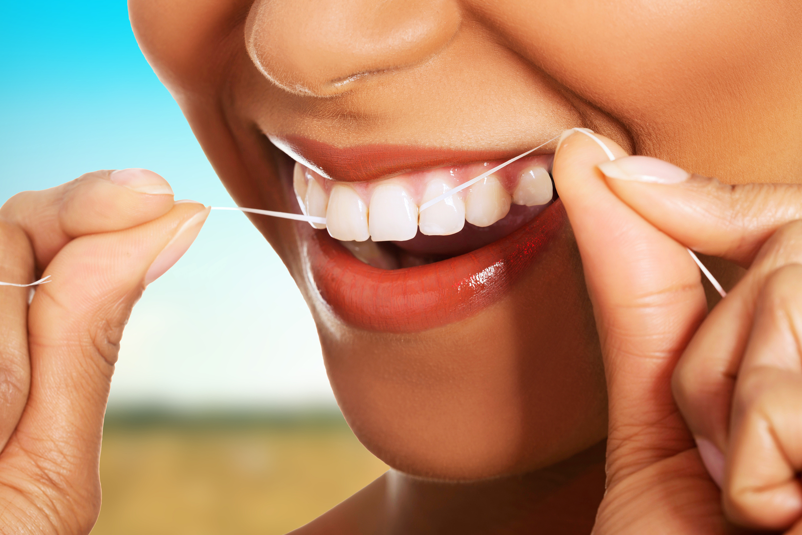 Beautiful woman using dental floss.